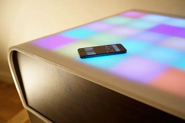 La table TA+BLE aux cases lumineuses multicolores, avec un iPhone sur le plateau.